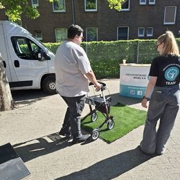 Eine Frau vom Kreissportbund erklärt einem Mann mit Rollator die Nutzung des Rollators.
