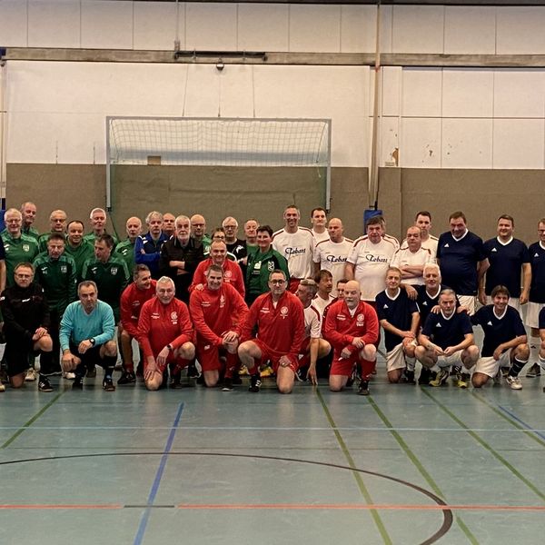 Gruppenfoto von mehreren Walking-Footballmannschaften, Schiedsrichtern und Ehrengästen in einer Sporthalle.