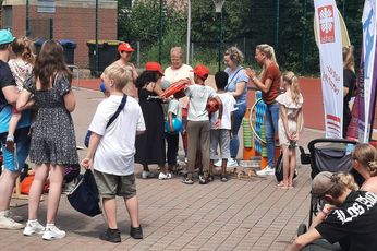 Viele Kinder stehen mit dem Rücken zur Kamera vor vier Frauen, die Geschenktüten für die Preisverleihung verteilen.