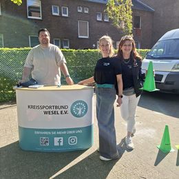 Drei Personen stehen vor einem Infostand mit Aufdruck "Kreissportbund Wesel e.V.".