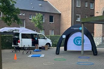 Der Stand des Kreissportbund Wesel. Im Hintergrund eine Mitarbeiterin des Kreissportbundes vor einem weißen Van und ein Zelt des Kreissportbundes. Im Vordergrund liegen Holzreifen, Matten und Pylonen.